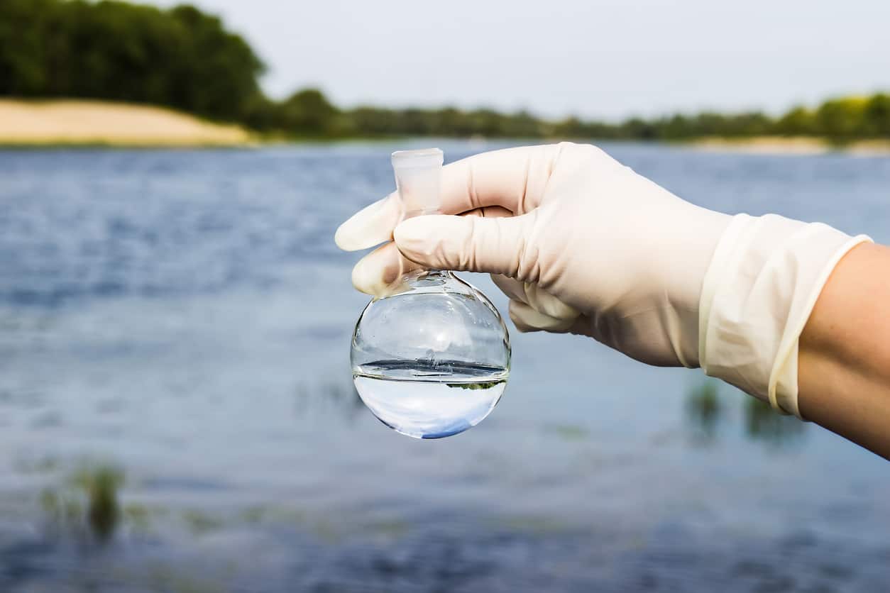 New York City water supply quality - A scientist's hand holding a flask of water sample.