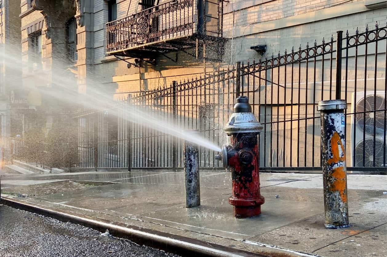 An open fire hydrant installed in a street releasing water.